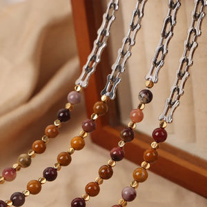 Silver asymmetrical chain necklace with mixed stone beads and gold accents.