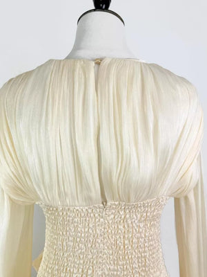 White ruffled mini dress with smocked corset waist detail and long sleeves.