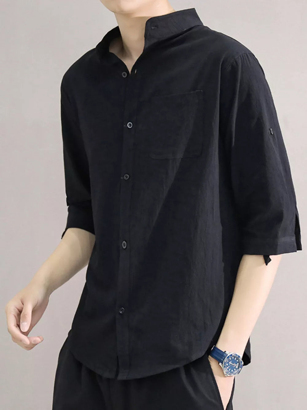 Black cotton button-down shirt with roll-up sleeves and chest pocket.