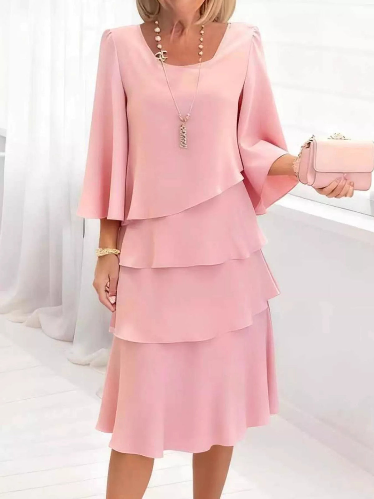 Elegant blush pink tiered dress with 3/4 bell sleeves and square neckline.