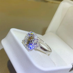 Radiant moissanite solitaire ring in silver with a large oval-cut center stone and small accent stones.