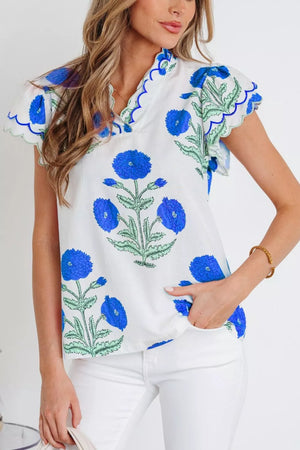 White cotton blouse with blue floral print, short sleeves, and scalloped neckline.