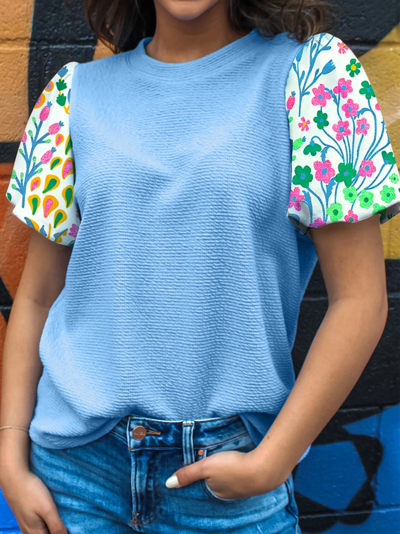 Light blue textured blouse with abstract floral bubble sleeves.