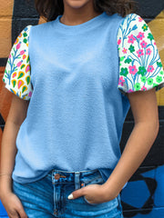 Light blue textured blouse with abstract floral bubble sleeves.