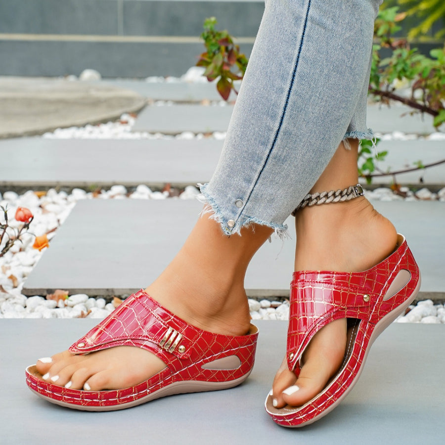 Red crocodile-embossed wedge sandals with thong strap and gold buckle detail.