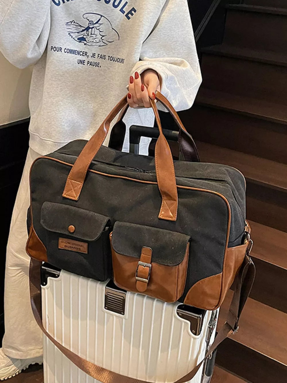 Black canvas travel bag with brown leather accents and multiple pockets.