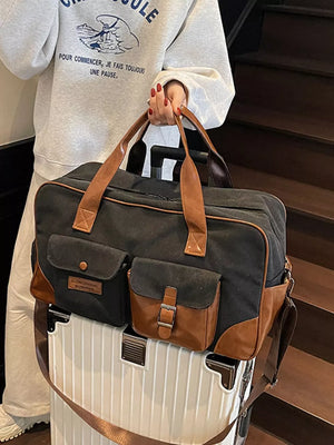 Black canvas travel bag with brown leather accents and multiple pockets.