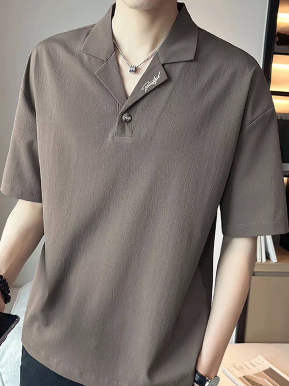 Taupe cotton polo shirt with embroidered detail and buttoned collar.