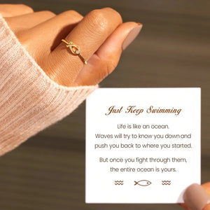 Gold ring with delicate fish motif and zircon detail on finger.