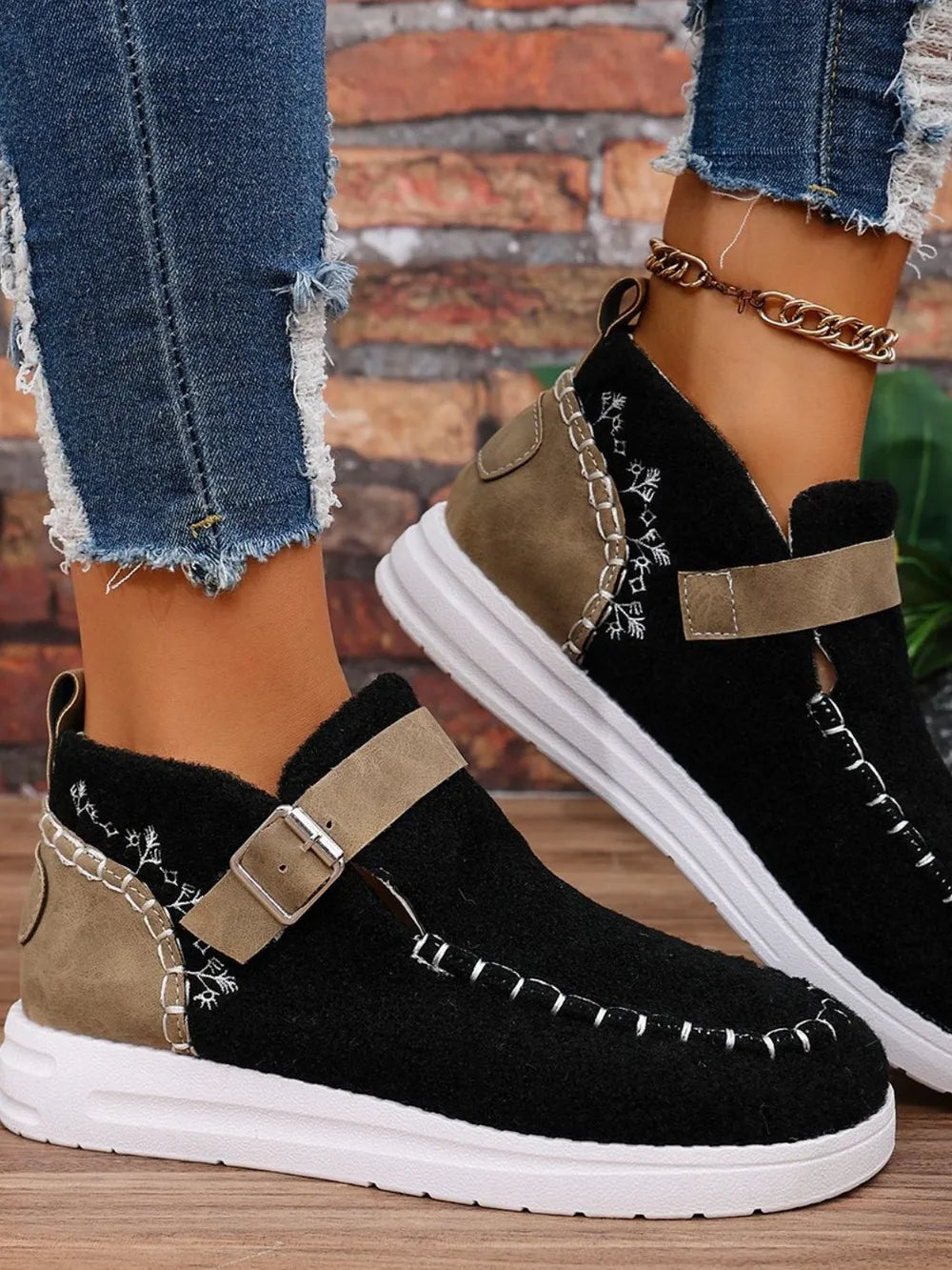 Black textured stitch-detail buckle sneakers with tan accents and white soles.