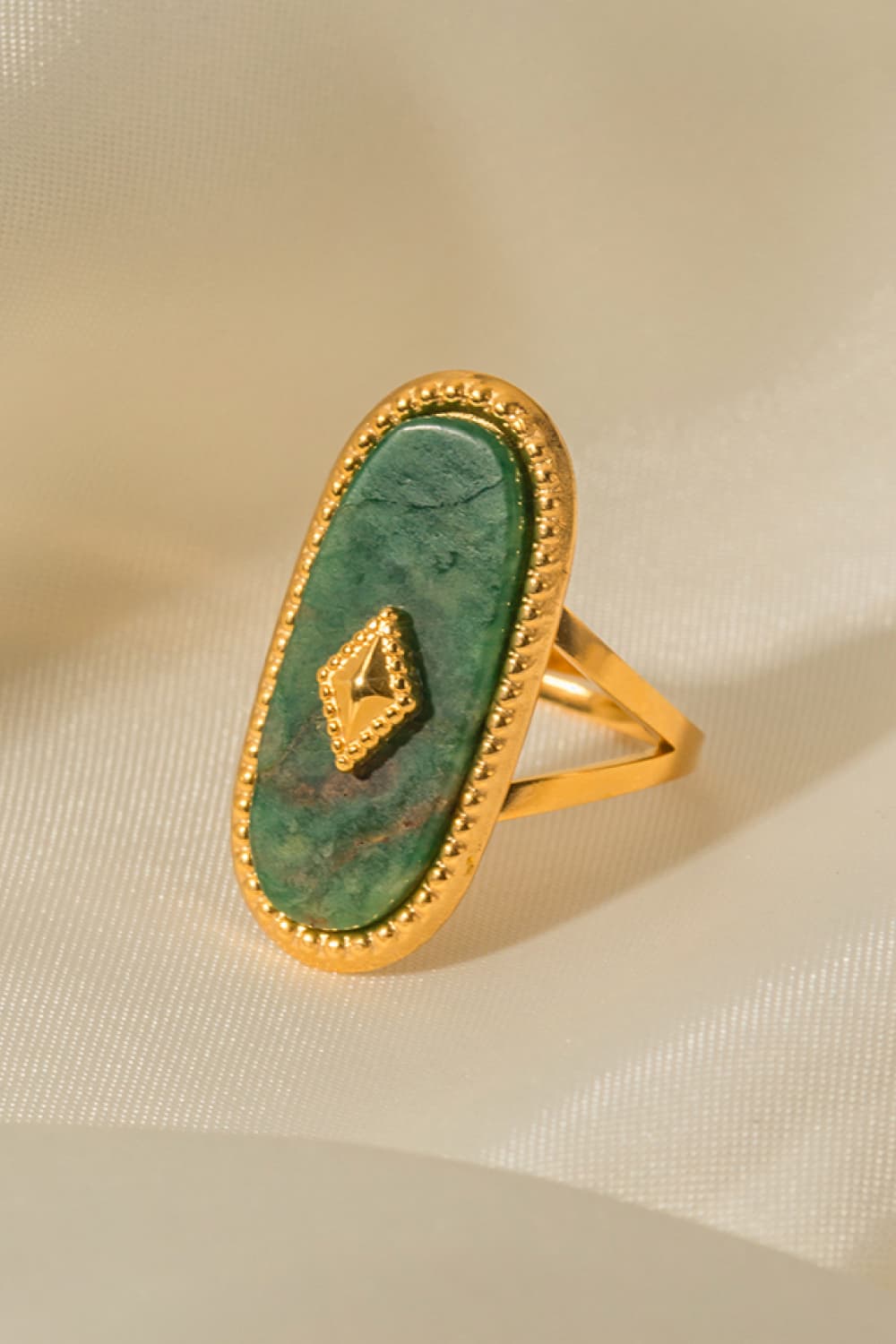 Gold-plated ring with oval green stone and diamond accent detail