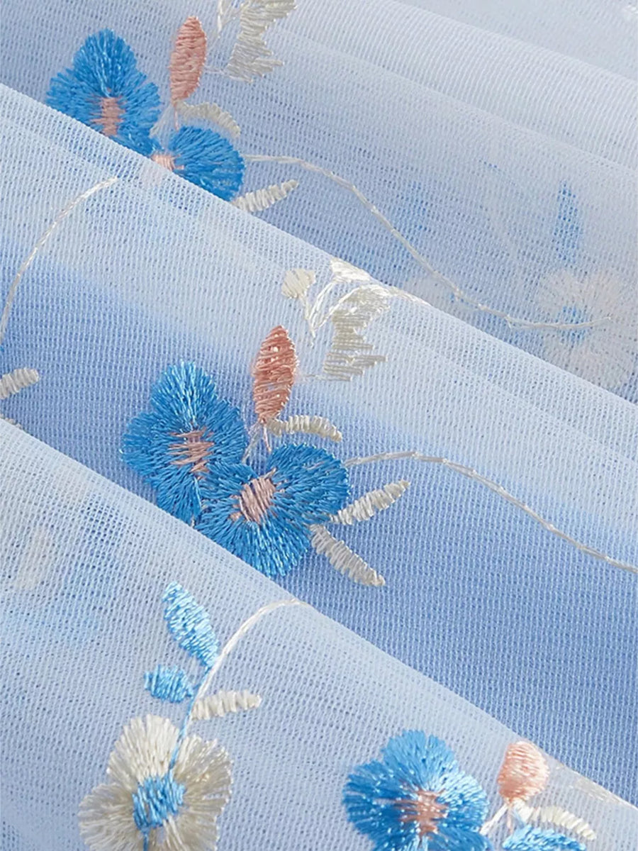 Blue mini dress with floral embroidery and tie shoulders.