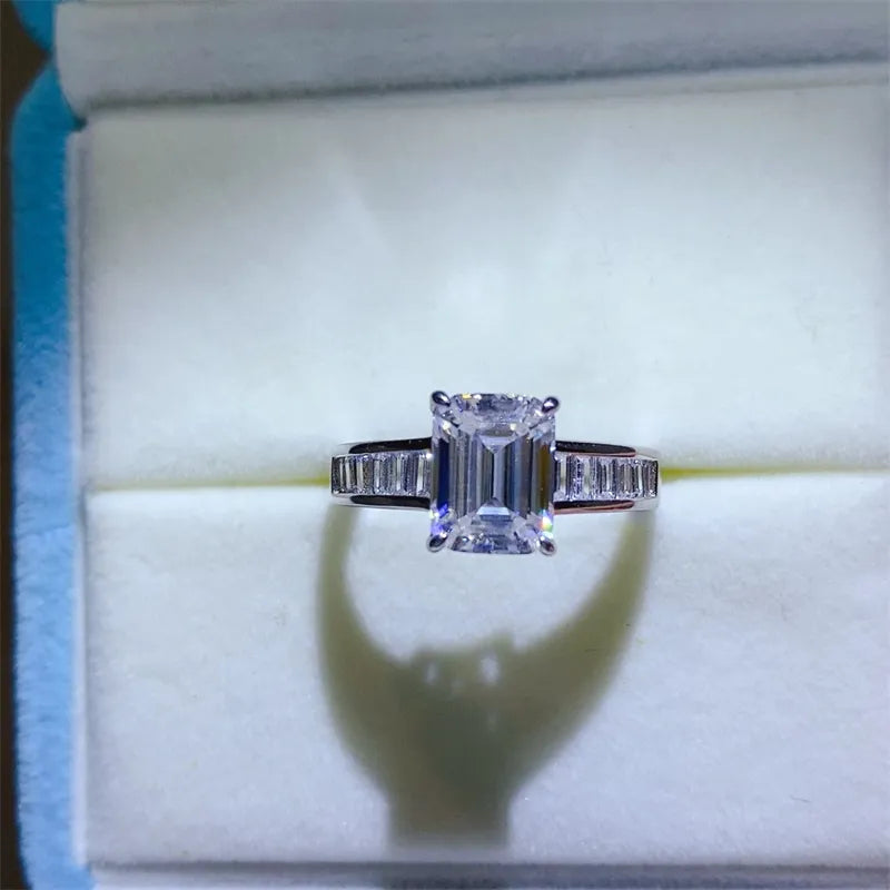 Emerald cut moissanite ring with baguette accents in silver.