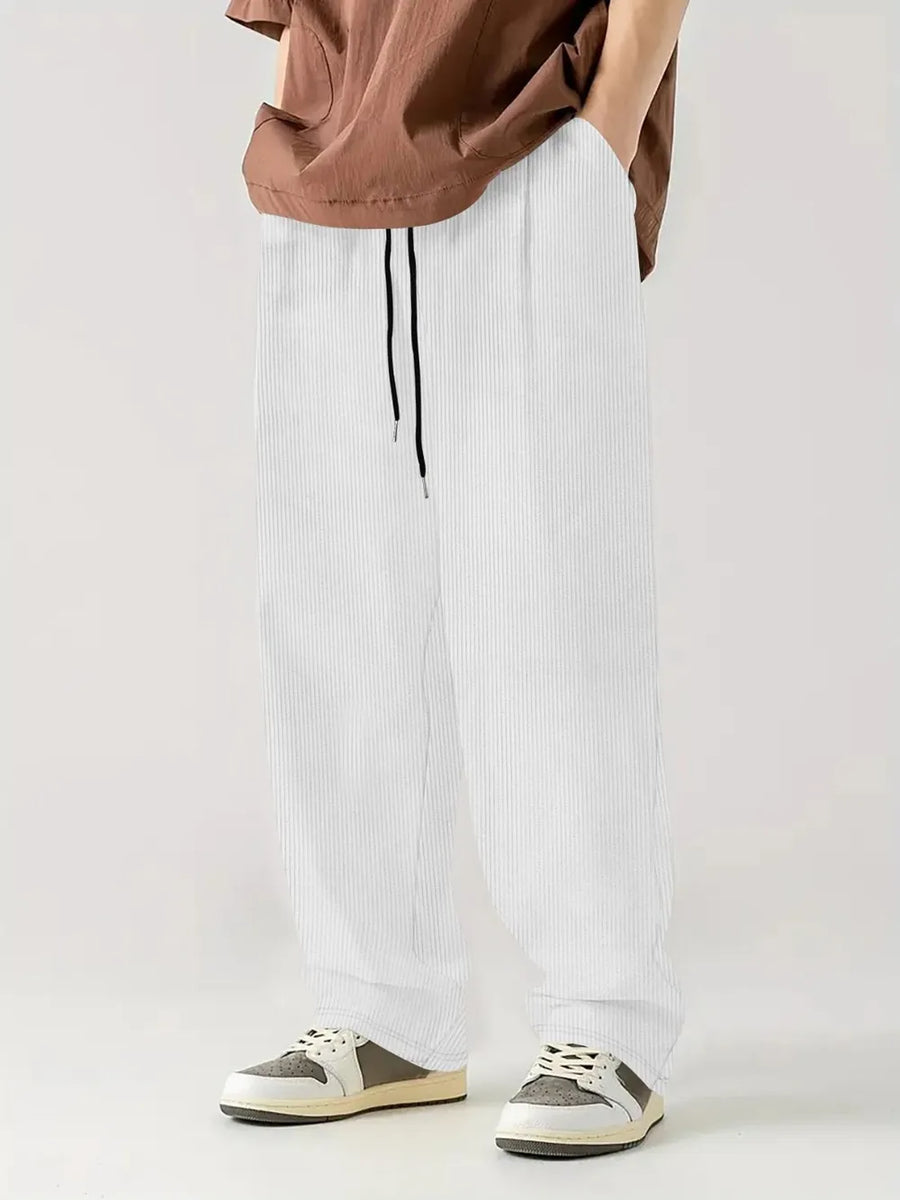 White corduroy relaxed fit trousers with drawstring waist and vertical texture.