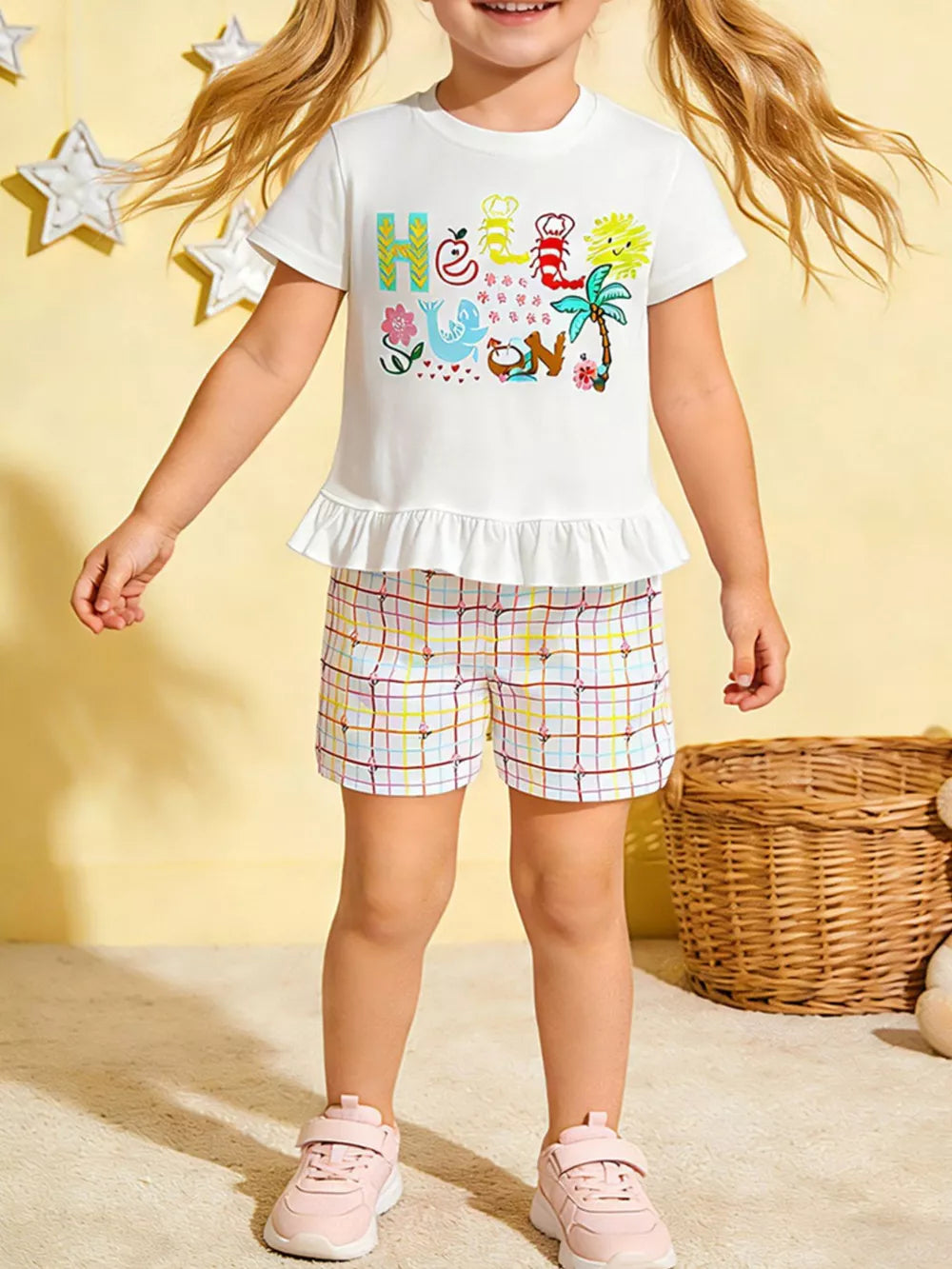 Girls' white cotton tee with ruffle hem and colorful graphic, paired with plaid shorts.