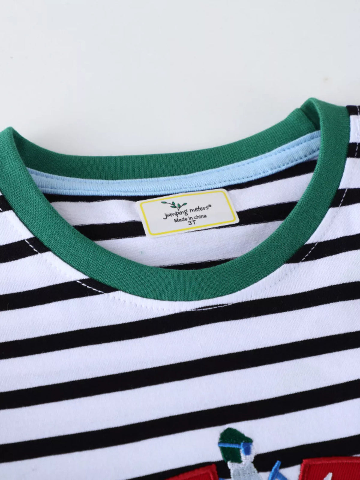 Baby black and white striped long-sleeve tee with green trim and racing car embroidery detail.