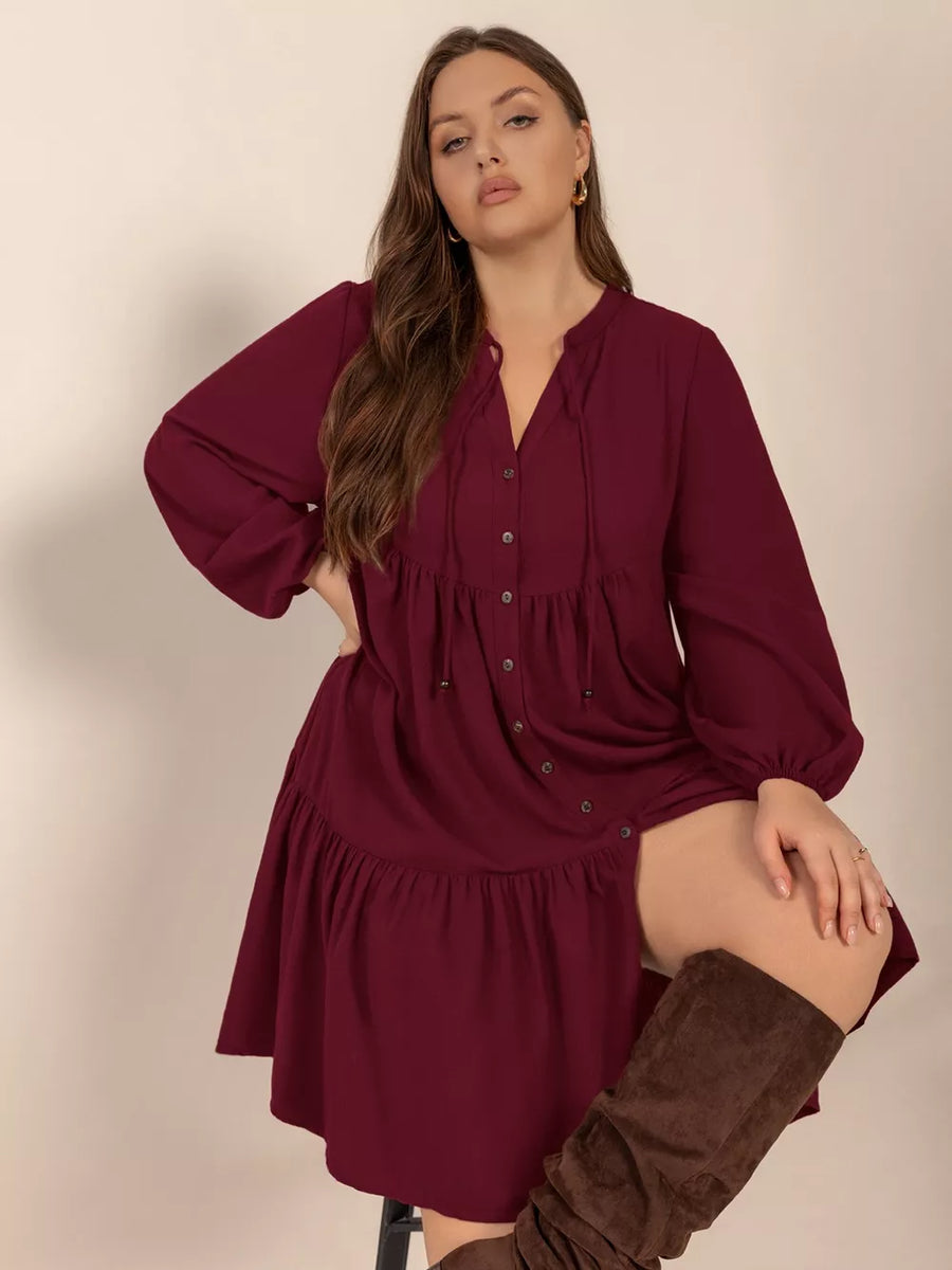 Plus-size burgundy tied balloon sleeve tiered dress with button front and ruffled hem.