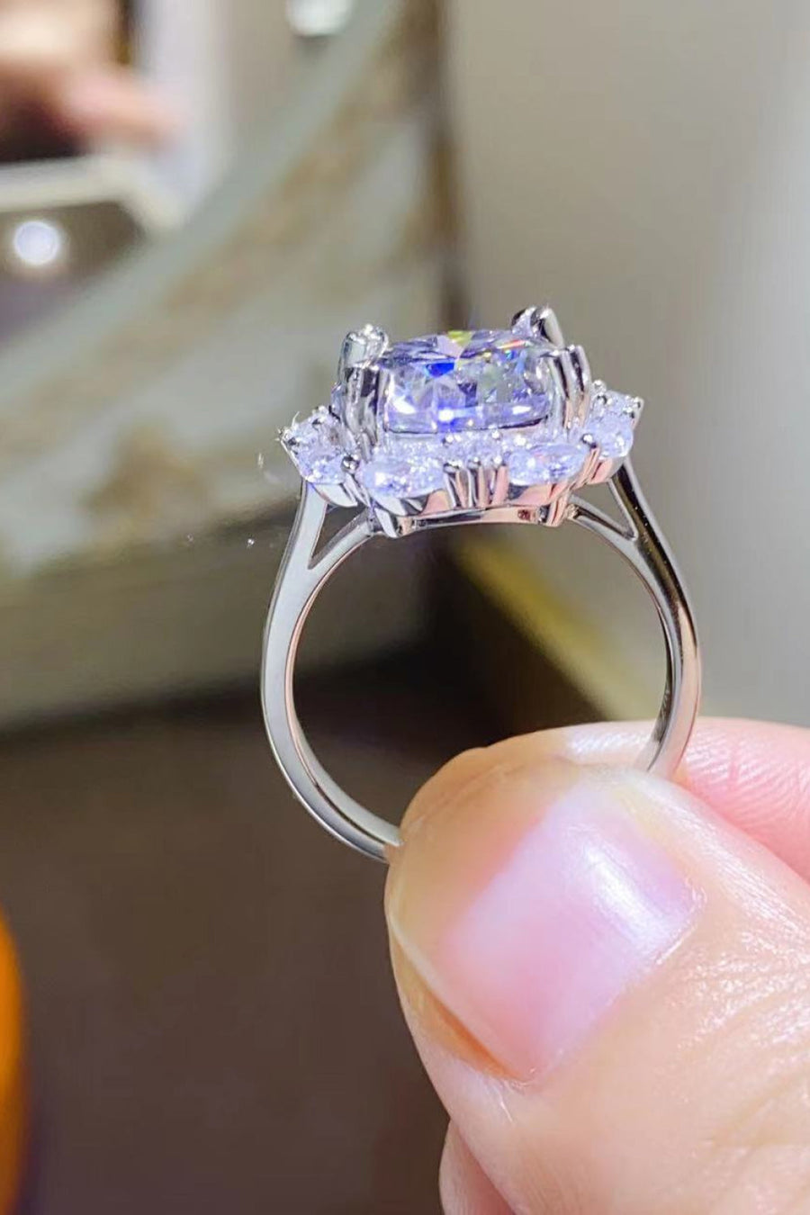 Silver moissanite halo ring with a large cushion-cut center stone.
