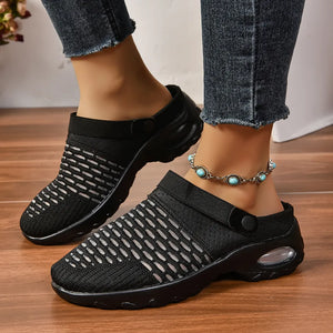 Black knit sport clogs with white woven detail and heel strap, featuring a clear air cushion sole.