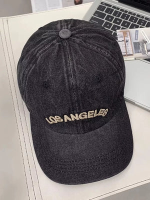 Black denim baseball cap with embroidered Los Angeles text, adjustable strap.