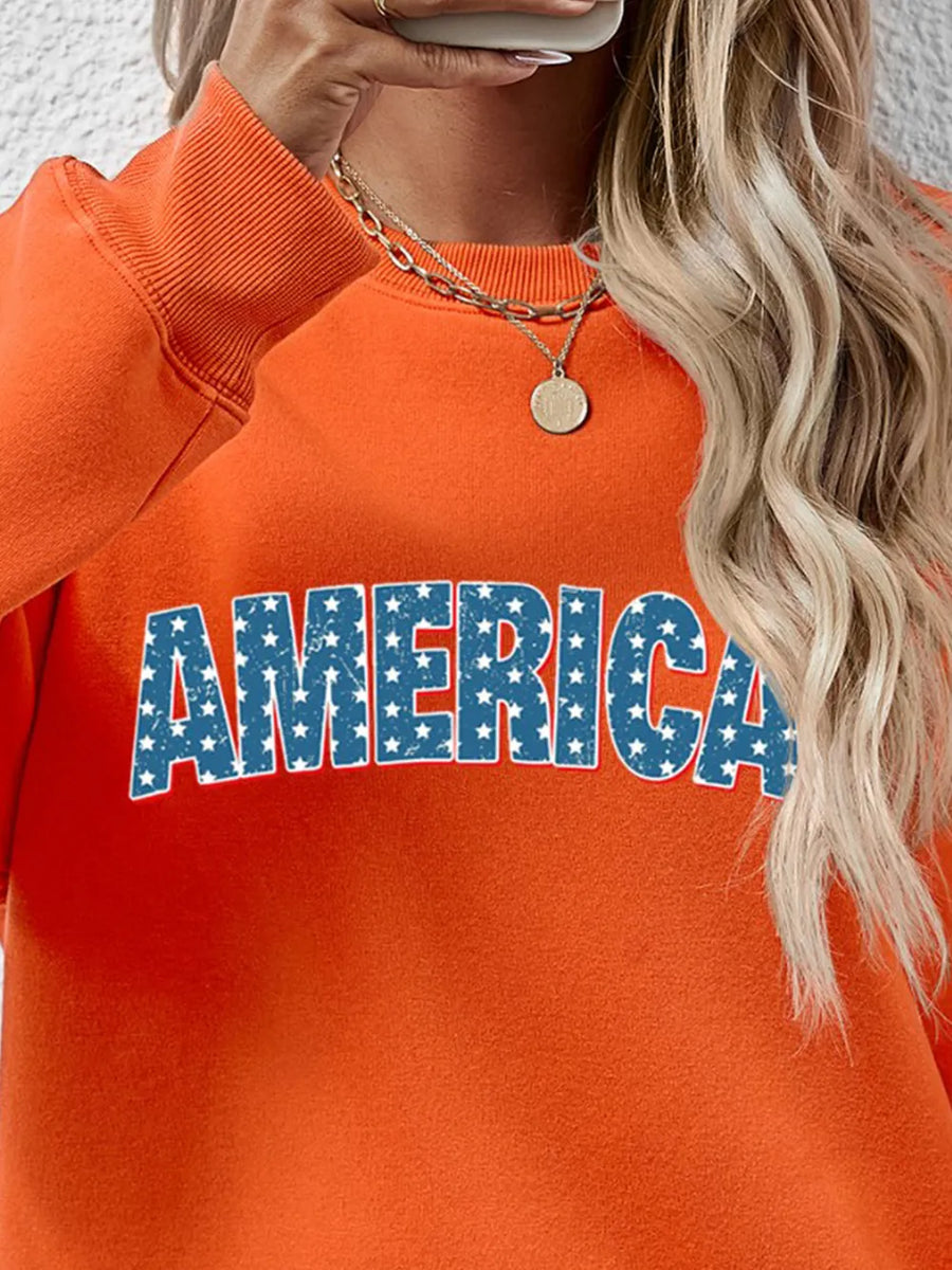Orange crewneck sweatshirt with distressed blue stars and white text graphic that says AMERICA.