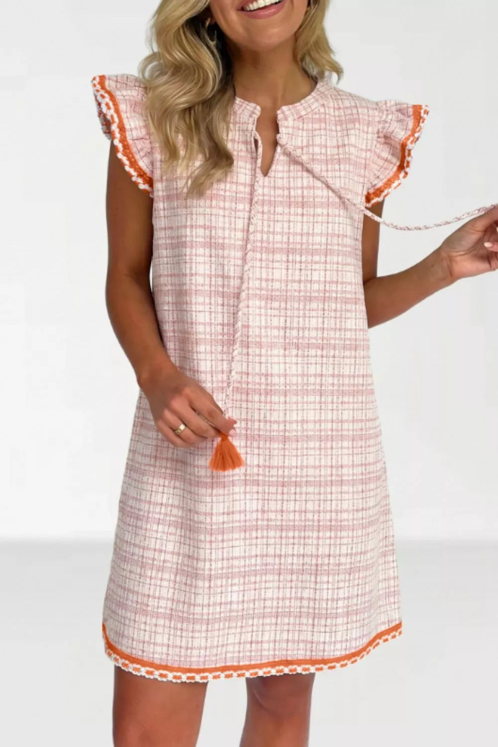Charming jacquard shift dress with ruffled trim, tie neck, and tassel detail.