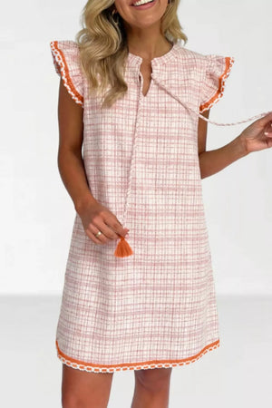 Charming jacquard shift dress with ruffled trim, tie neck, and tassel detail.