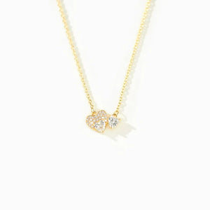 Gold necklace with two heart-shaped zirconia charms, one paved with small stones.