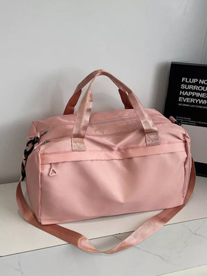 Pink duffel bag with dual handles and adjustable shoulder strap, front zip pocket.