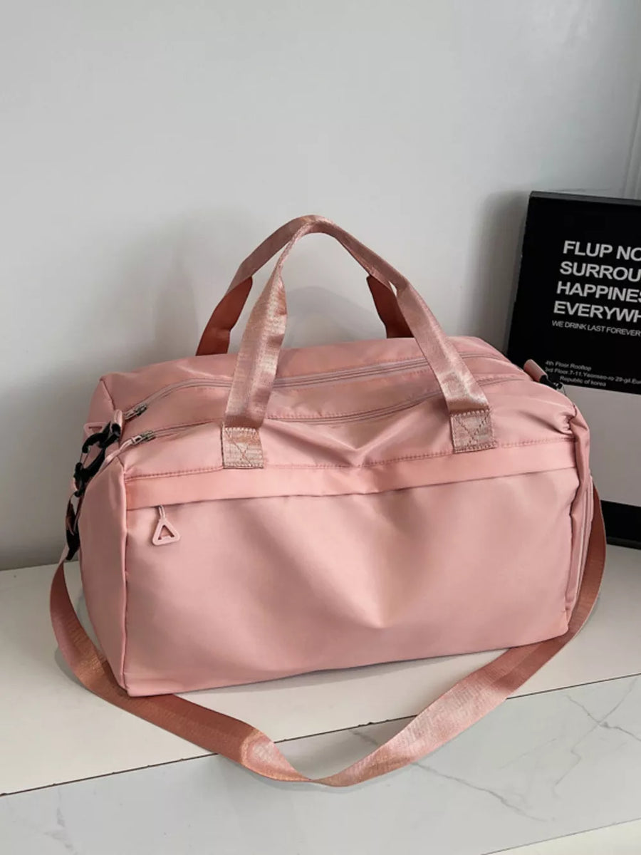 Pink duffel bag with dual handles and adjustable shoulder strap, front zip pocket.