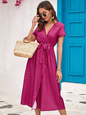 Wrap dress in magenta with red polka dots, V-neck, short sleeves, tie waist, and midi length.