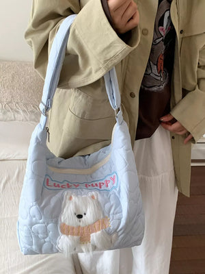 Light blue quilted crossbody bag with a white bear applique and "Lucky puppy" text.