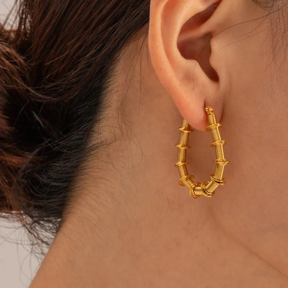 Gold coiled wire hoop earrings with textured segments