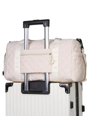 Diamond-quilted off-white travel bag with front zipper pocket and luggage sleeve.