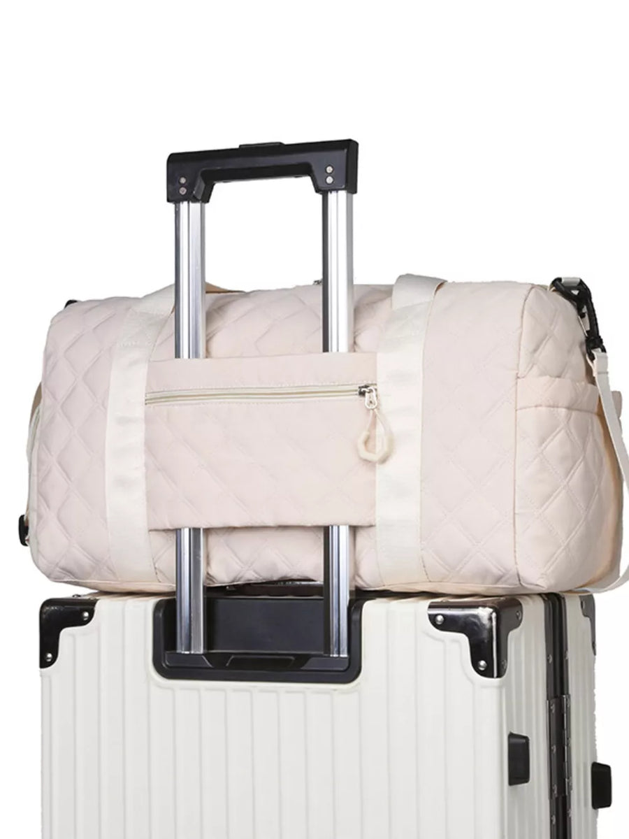 Diamond-quilted off-white travel bag with front zipper pocket and luggage sleeve.