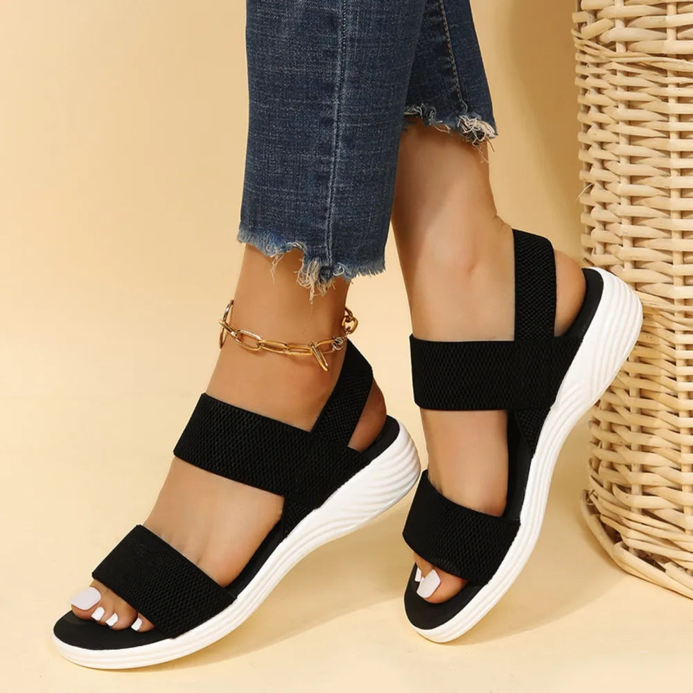Black knit strap sandals with white soles and a gold anklet.