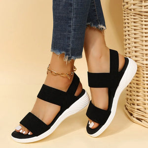Black knit strap sandals with white soles and a gold anklet.
