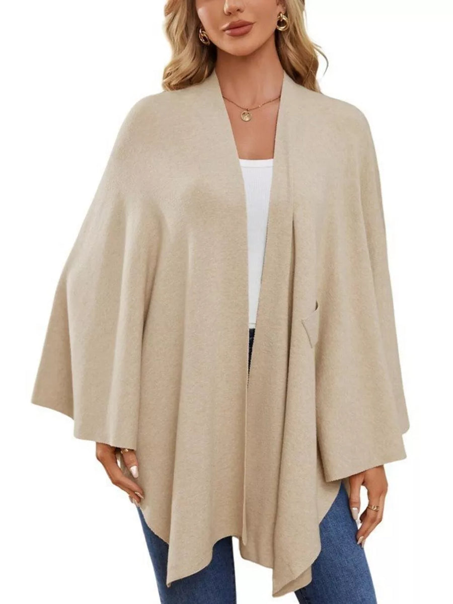 Beige knit cape top with draped elegance and tie front detail.