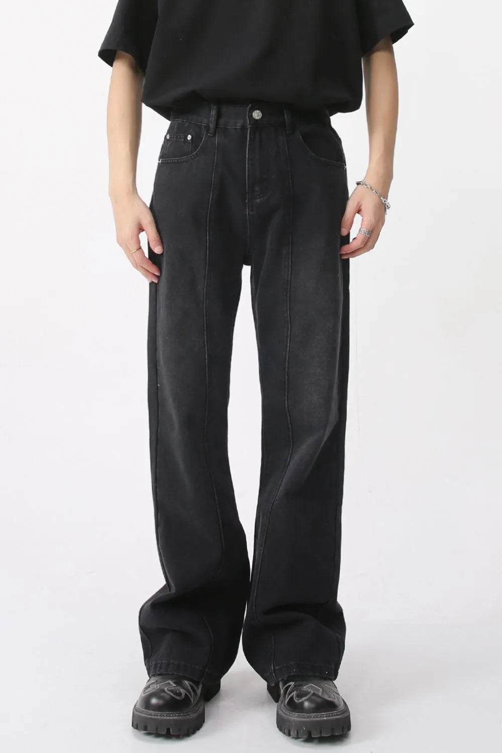 Dark wide-leg denim trousers with vertical seams and a relaxed fit.