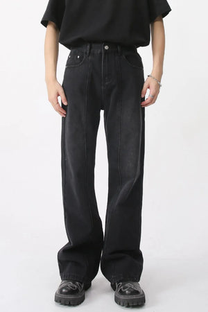 Dark wide-leg denim trousers with vertical seams and a relaxed fit.