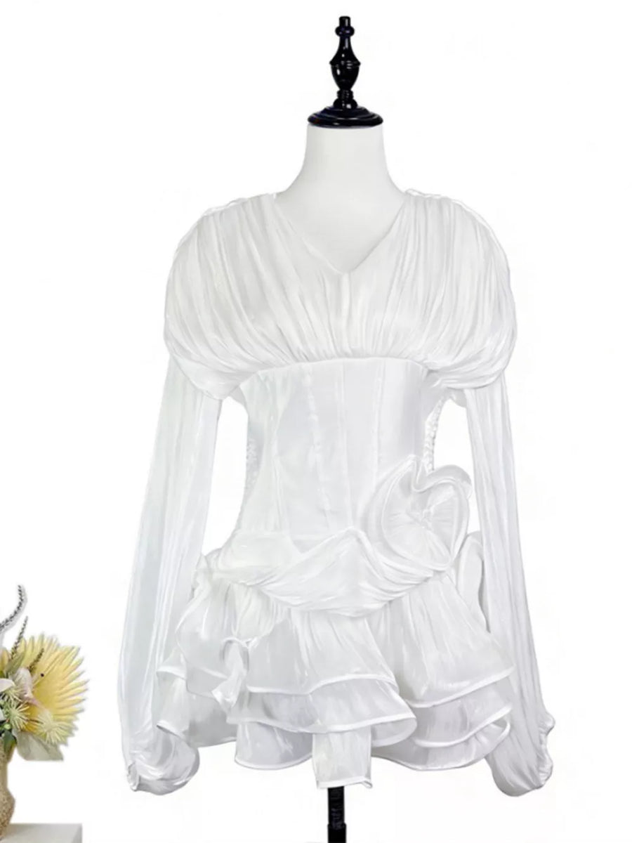 White cotton mini dress with corset waist, ruffled skirt, and long sheer sleeves.