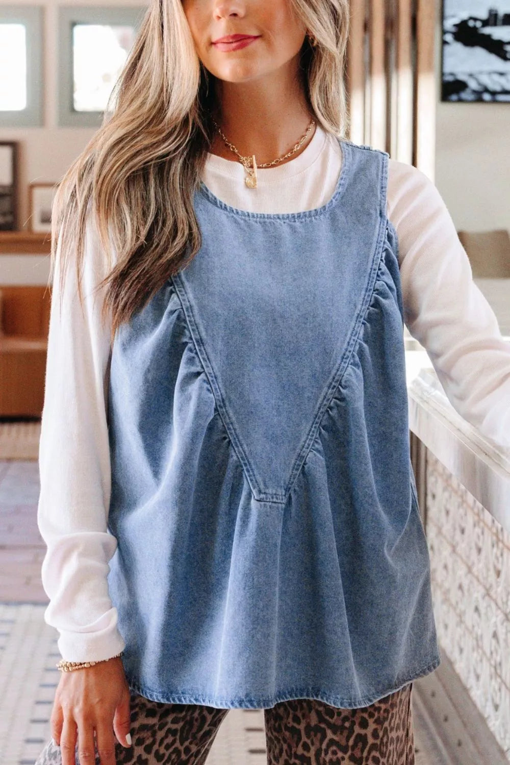 V-shaped pleated denim sleeveless top with a rounded neckline.