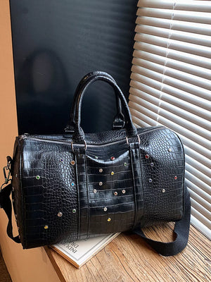 Black crocodile textured duffel bag with colorful studs and detachable strap