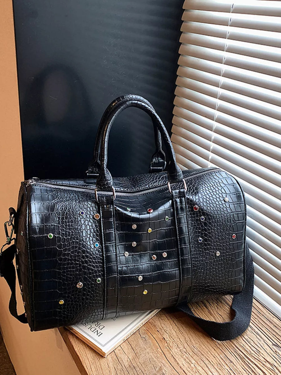 Black crocodile textured duffel bag with colorful studs and detachable strap