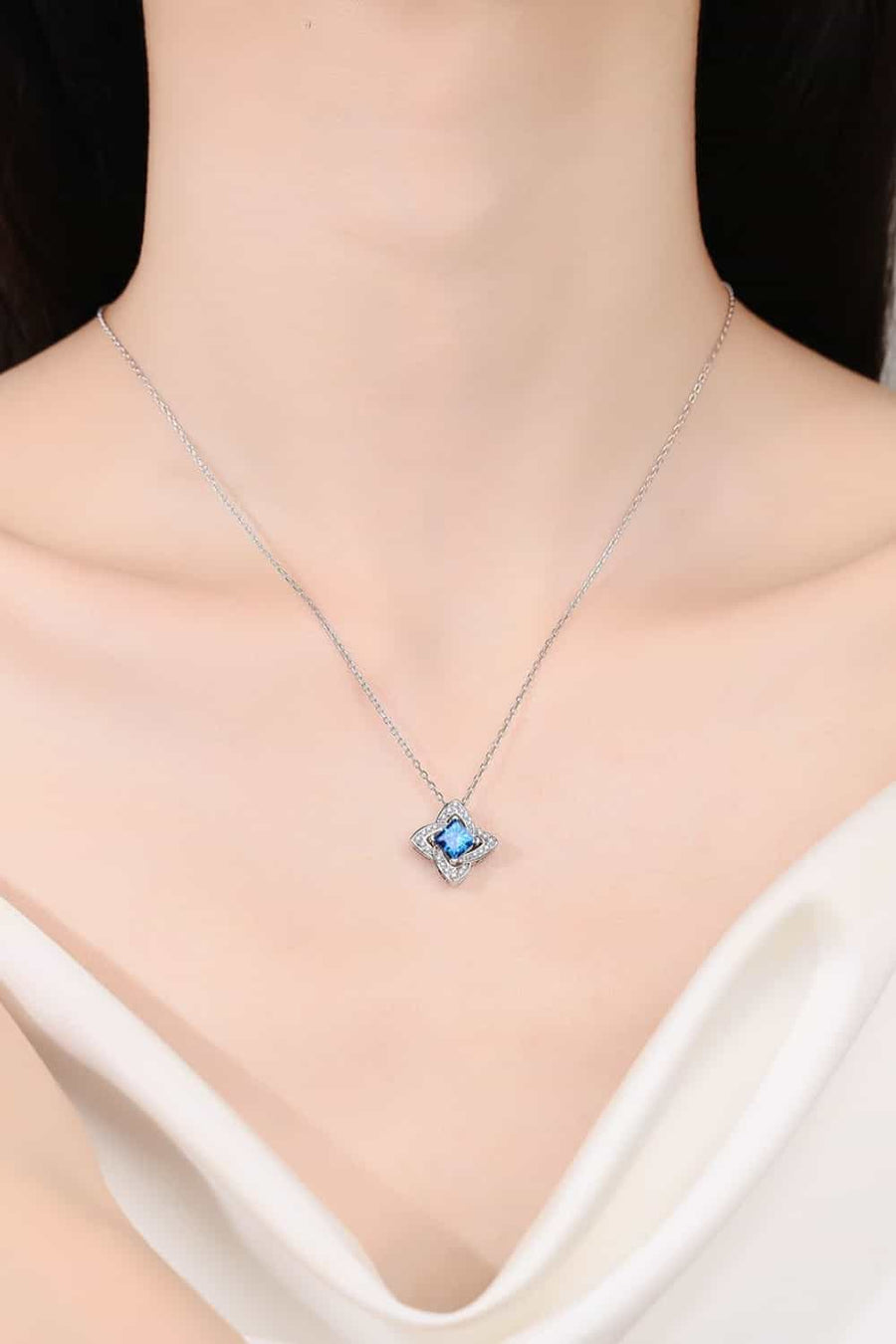 Sky blue moissanite and diamond pendant necklace with a floral design.