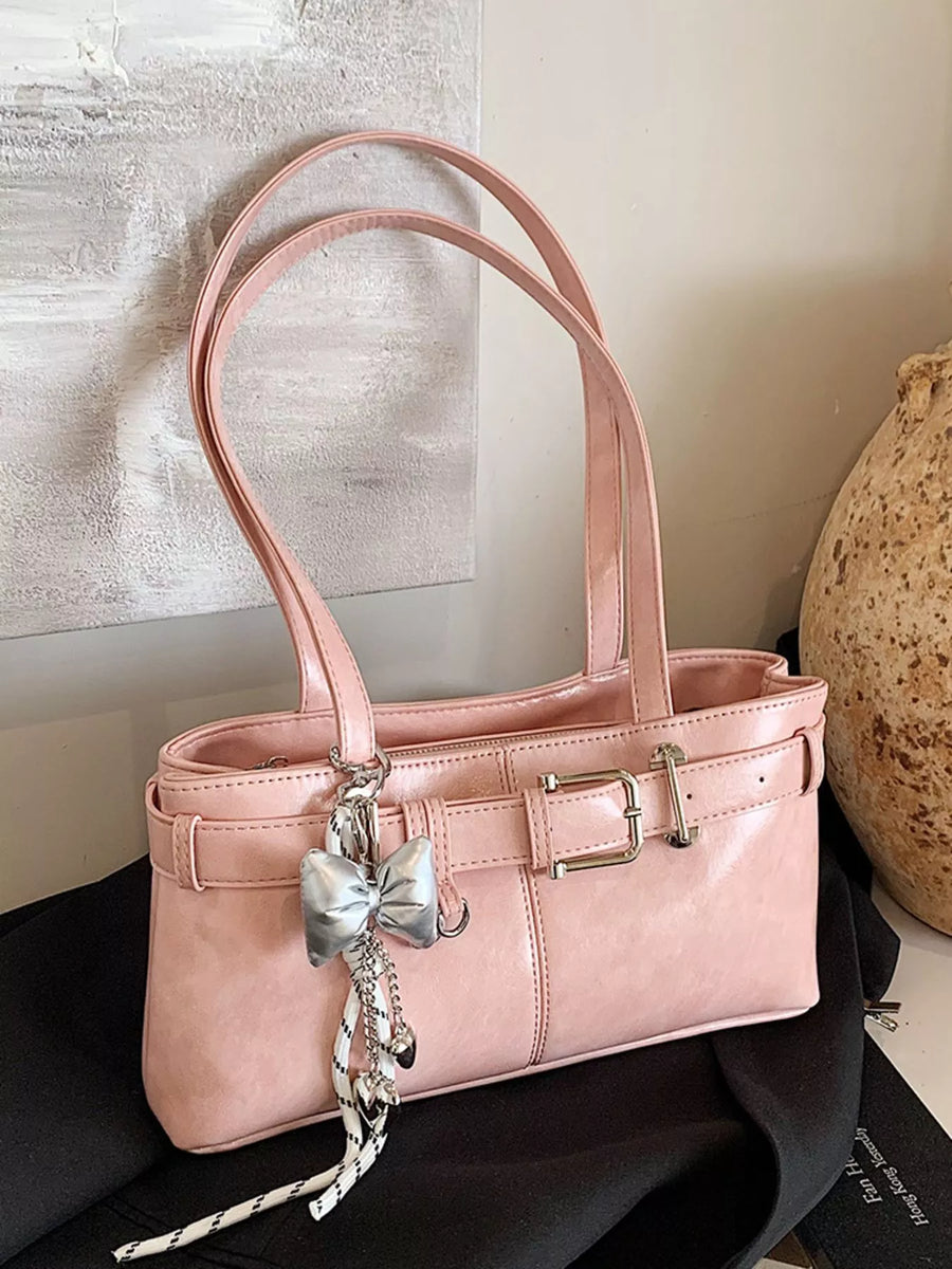 Blush pink shoulder bag with buckle detail and silver bow charm.