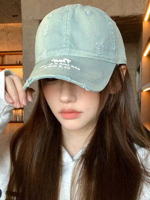 Distressed baseball cap in dirty blue cotton with embroidered detail and frayed brim.