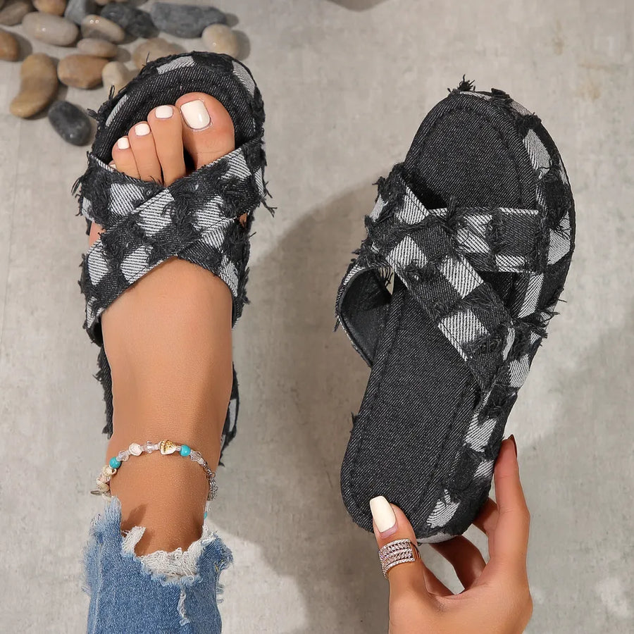 Distressed denim checkered platform slides in black with crisscross straps and frayed edges.
