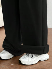 Black wide-leg maternity joggers with cuffed hems, styled with white sneakers.
