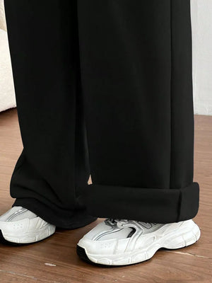 Black wide-leg maternity joggers with cuffed hems, styled with white sneakers.